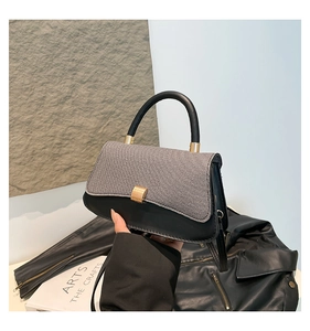 Detail of contrast stitch handbag featuring woven flap and gold rectangular buckle lock