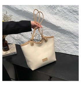 Detail of the drawstring closure and brown knotted handles on the cream tote bag