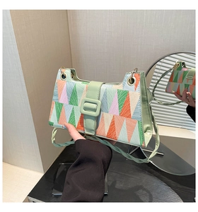 Detail of color-block geometric pattern underarm bag with gold eyelets and leather strap