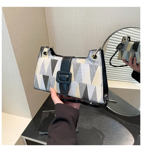 Detail of color-block shoulder bag with geometric triangle pattern and metal buckle