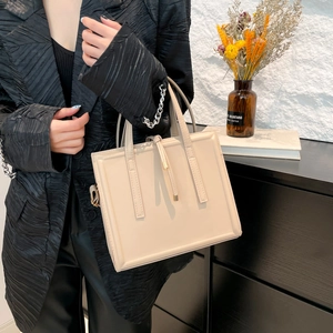 Minimalist beige structural square handbag with delicate stitching and metal tipped drawstring