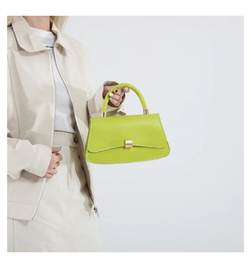 Dettaglio della borsa verde lime con fibbia dorata abbinata a una giacca color crema