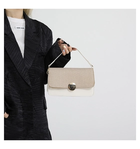 Close-up of color-block handbag featuring a beige woven flap and large marble-style buckle