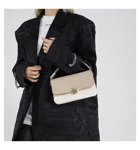 Detail of a contrast flap bag featuring beige woven texture and gold circular buckle