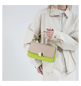 Close-up of green leather handbag with beige woven flap and golden metal clasp