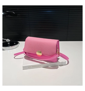 Detail of pink crossbody bag featuring textured fabric flap and gold circular buckle