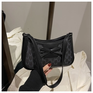 Detail of vintage monogram M print and leather bow on black baguette shoulder bag