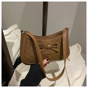 Detail of brown monogram shoulder bag featuring a decorative leather bow and silver hardware