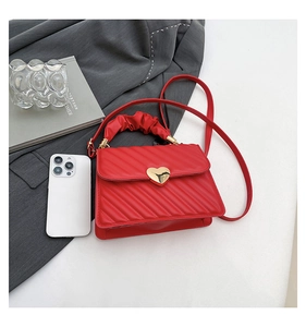 Detail of red quilted small square bag with golden heart clasp and ruched cloud handle