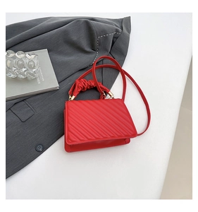 Detail of red quilted faux leather handbag with ruffled handle and gold hardware