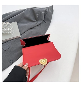 Detail of red leather crossbody bag featuring a golden heart-shaped metal twist lock