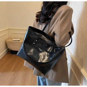Detailed view of the large black faux leather tote bag worn on a shoulder for commuting
