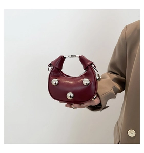 Detail of burgundy heart bag with silver metallic studs and soft leather texture