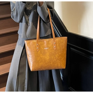 Detail of caramel tote bag showing silver rivets and high-capacity minimalist design