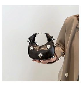 Detail of black leather crescent mini bag with large silver bead studs and metal clasp