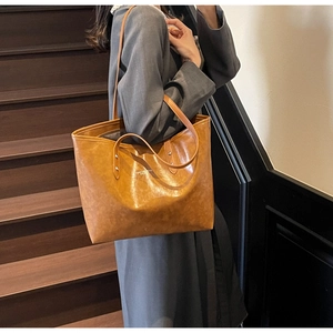Close-up of vintage brown tote bag with oily leather texture on a female model