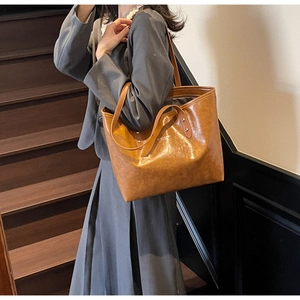 Close-up of brown polished leather tote bag showing glossy texture and shoulder straps