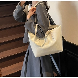 Detail shot of off-white faux leather tote bag showing smooth texture and metal rivets
