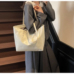 Detailed close-up of cream white tote bag texture with metal rivet on leather strap