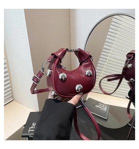 Detail of burgundy crescent mini bag with glossy leather and silver metal ball studs