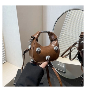 Detail of a mini brown crescent bag with silver stud accents and unique folding handle