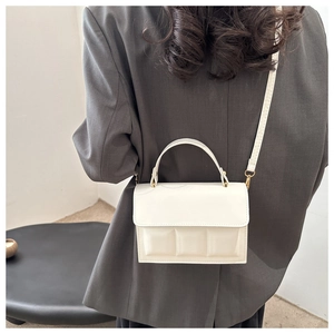 Detail of white rectangular bag featuring 3D embossed square patterns and matte texture