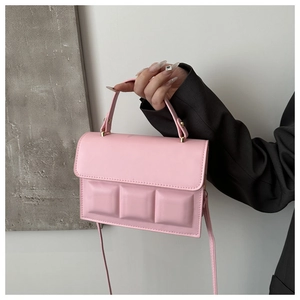 Detailed close-up of pink chocolate-style square handbag with 3D grid and gold hardware