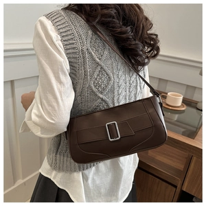Close-up of dark brown leather baguette bag with a silver square buckle on a model