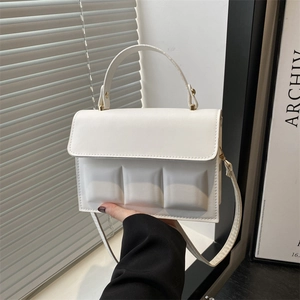 Detail of white square-embossed bag with gold hardware and smooth handle
