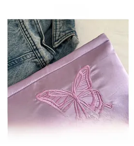 Close-up of premium purple satin handbag featuring intricate butterfly embroidery detail