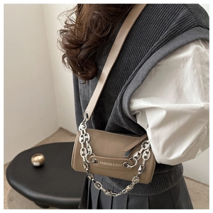 Detail of a brown cylindrical crossbody bag with metal chain strap and luxury leather texture