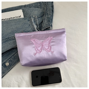 Close-up of purple satin pouch with pink butterfly embroidery and a zip closure