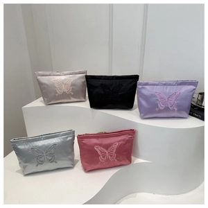 Macro detail of elegant butterfly embroidery on satin mini bag with zipper top