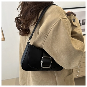 Gros plan d'un sac sous le bras en cuir noir avec une grande boucle argentée sur un mannequin