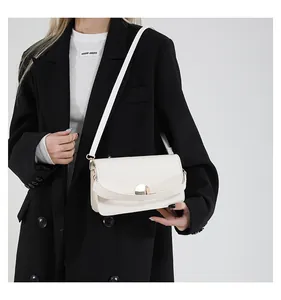 Détail d'un sac à bandoulière en cuir blanc cassé avec fermoir rond en métal doré