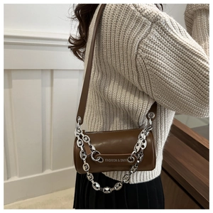Close-up of brown cylindrical crossbody bag with chunky silver mariner chain detail
