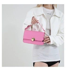 Détail d'un sac à main rectangulaire rose vif avec une boucle ronde dorée élégante
