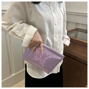 Detail of premium purple satin clutch with 3D pink butterfly embroidery being held