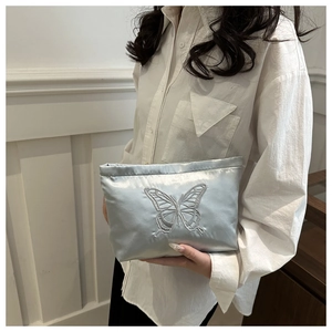 Detailed close-up of silver satin tote bag featuring intricate butterfly embroidery texture