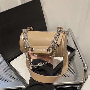 Detail of khaki cylindrical crossbody bag showing silver chain and leather strap