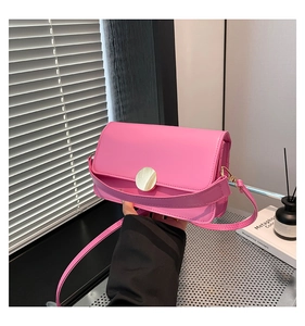 Detail view of pink rectangular handbag featuring a polished gold circular metal clasp