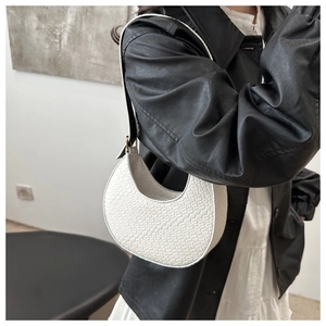 Détail du sac croissant blanc avec texture tressée et bandoulière en cuir noir