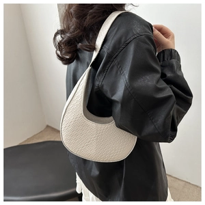 Détail de la texture tressée beige et forme en croissant d'un sac à bandoulière chic