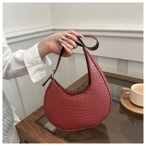 Détail du sac croissant tissé bordeaux montrant la texture et la bandoulière