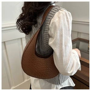Detail showing brown woven crescent hobo bag with adjustable strap in a lifestyle setting