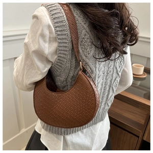 Détail du motif crocodile marron sur le sac en demi-lune porté par le mannequin