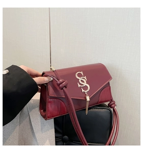Detail of burgundy tassel handbag showing smooth and crocodile pattern leather textures