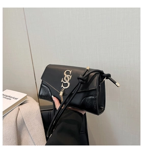 Detail of black handbag showing crocodile embossed leather, gold logo and chain tassel