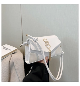 Detail of white PU leather crossbody bag with beige crocodile texture and gold tassel
