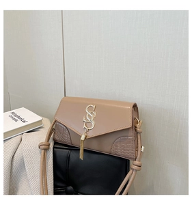 Detail of khaki leather crossbody bag featuring metal tassel and textured crocodile trim